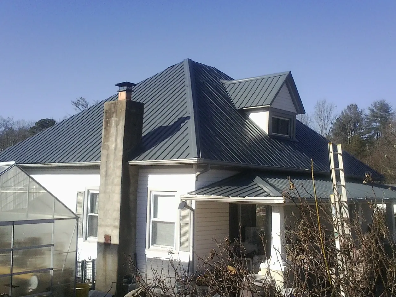 Dark blue standing seam metal roof on a white farmhouse with dormer — Slate & Tile Roof Repair by Roofing Brothers in Tower City