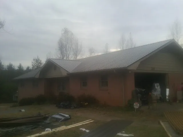 Gray metal roof on a stucco house with an attached garage in Tower City