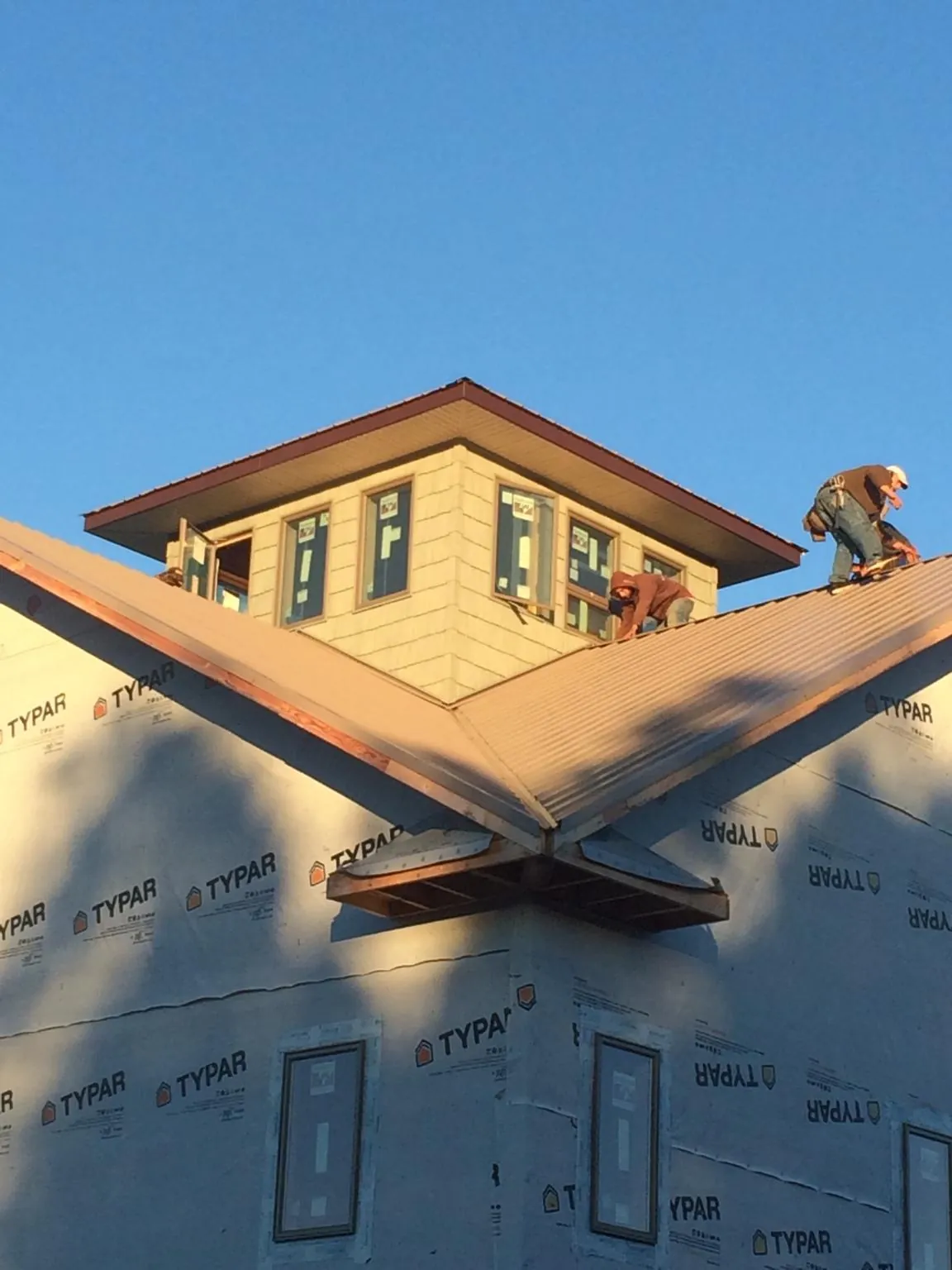 Roofers working around a rooftop cupola on a new metal roof at sunset — Roof Waterproofing in Tower City by Roofing Brothers